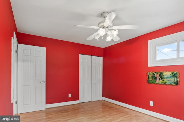 unfurnished bedroom featuring ceiling fan, a closet, baseboards, and wood finished floors