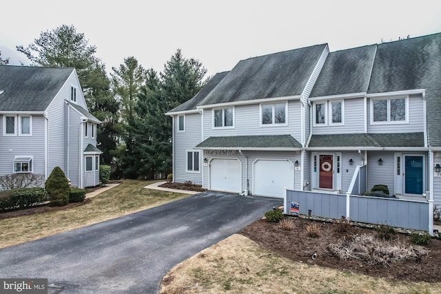 townhome / multi-family property featuring a garage, driveway, and a shingled roof