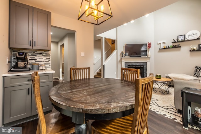 dining area with stairs, a chandelier, dark wood-style floors, and a fireplace