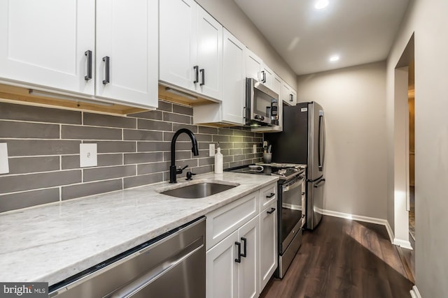 kitchen with dark wood-type flooring, a sink, light stone counters, white cabinetry, and stainless steel appliances