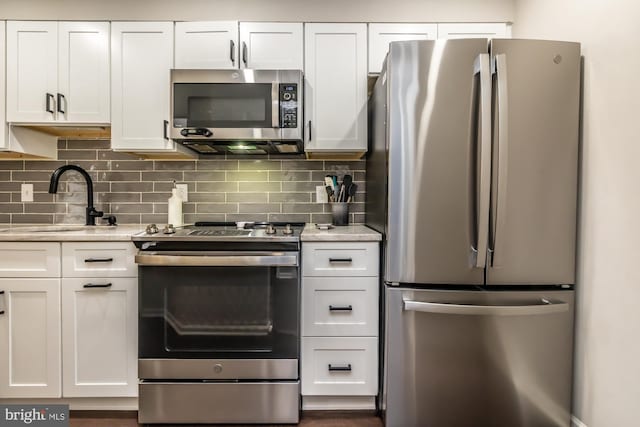 kitchen featuring tasteful backsplash, appliances with stainless steel finishes, white cabinetry, and a sink