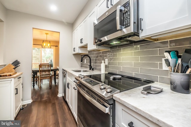 kitchen with dark wood-style flooring, a sink, decorative backsplash, appliances with stainless steel finishes, and white cabinetry