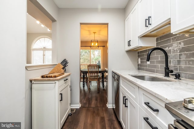 kitchen with white cabinetry, a sink, dark wood-type flooring, dishwasher, and tasteful backsplash