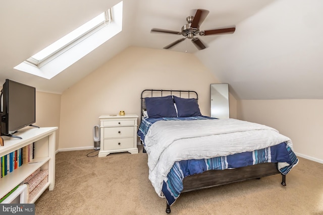 carpeted bedroom featuring lofted ceiling with skylight, a ceiling fan, and baseboards