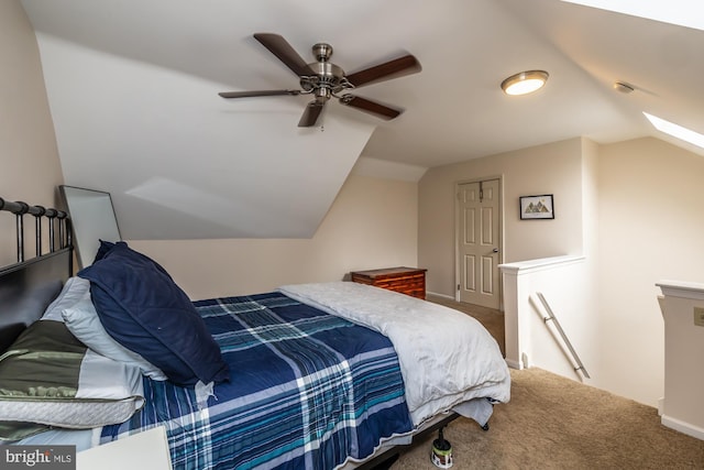 carpeted bedroom featuring vaulted ceiling with skylight, baseboards, and ceiling fan