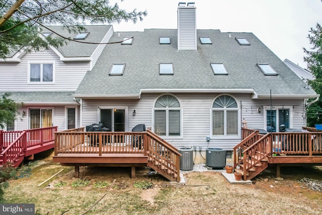 rear view of property with a wooden deck, cooling unit, a chimney, and a shingled roof