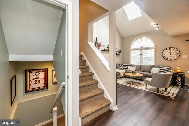 stairway featuring vaulted ceiling with skylight, wood finished floors, and baseboards