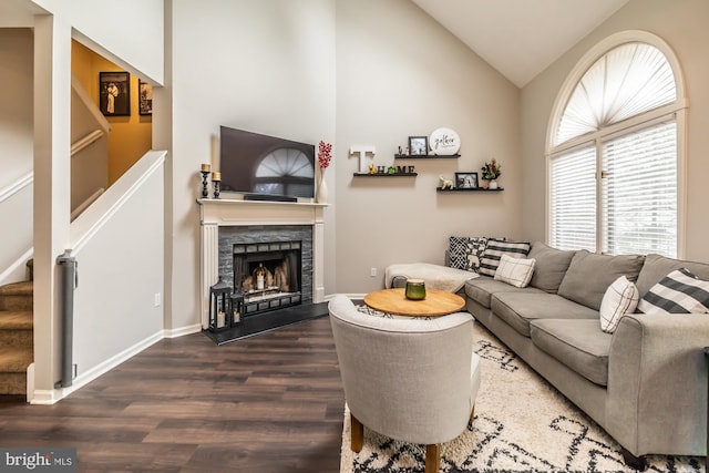 living room featuring baseboards, dark wood finished floors, stairway, lofted ceiling, and a fireplace