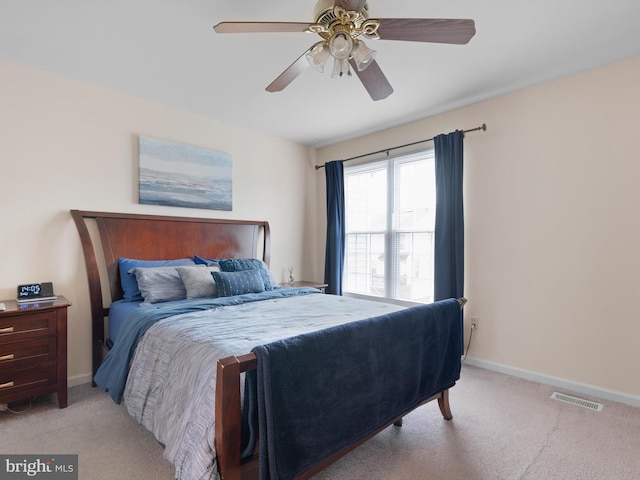 bedroom with ceiling fan, light colored carpet, visible vents, and baseboards