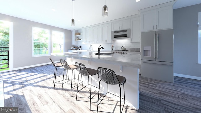 kitchen featuring tasteful backsplash, baseboards, refrigerator with ice dispenser, a kitchen breakfast bar, and a sink