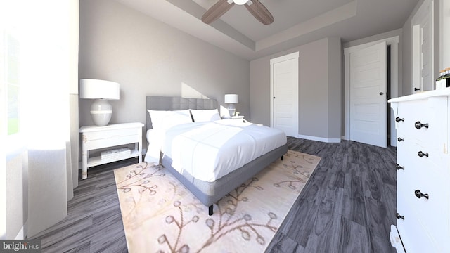 bedroom featuring a ceiling fan, a raised ceiling, wood finished floors, and baseboards