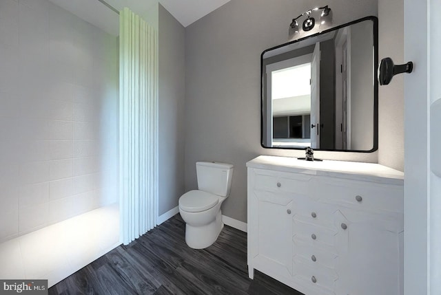 bathroom with baseboards, toilet, wood finished floors, and vanity