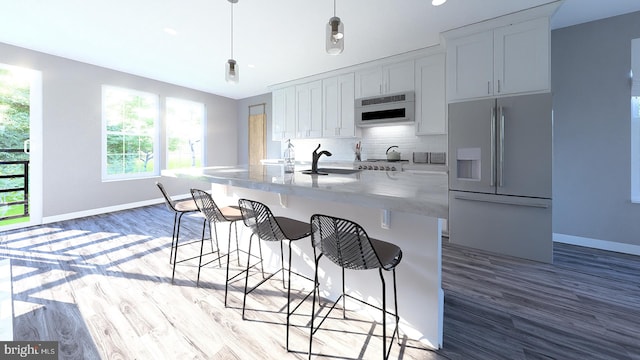 kitchen featuring backsplash, baseboards, a breakfast bar area, refrigerator with ice dispenser, and a sink