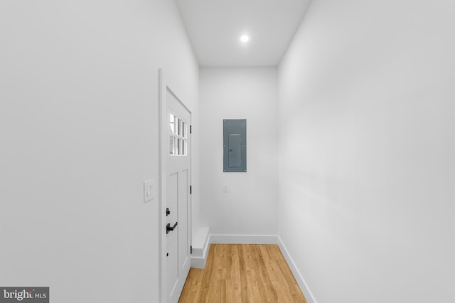 doorway to outside with electric panel, baseboards, and light wood finished floors