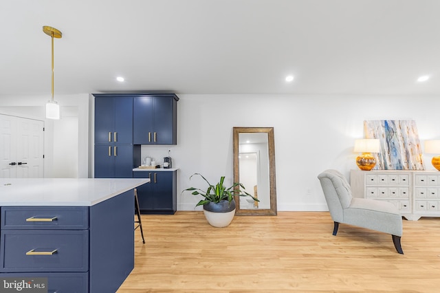 kitchen with blue cabinets, light wood-style floors, pendant lighting, and light countertops