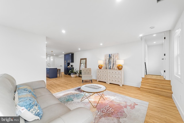 living area featuring stairway, recessed lighting, baseboards, and light wood-style floors