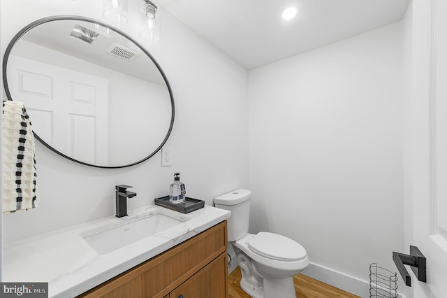 bathroom with visible vents, toilet, wood finished floors, baseboards, and vanity