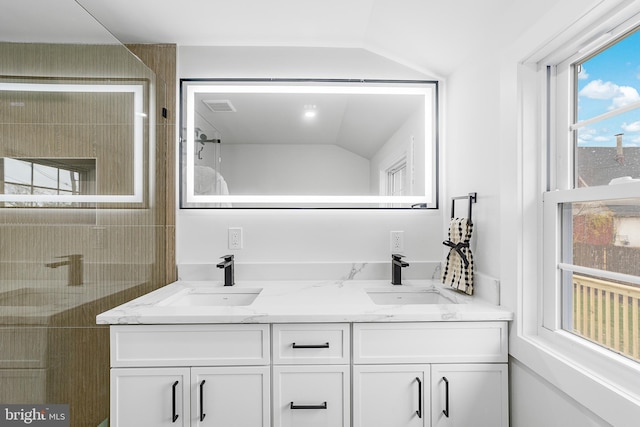 bathroom with double vanity, vaulted ceiling, visible vents, and a sink