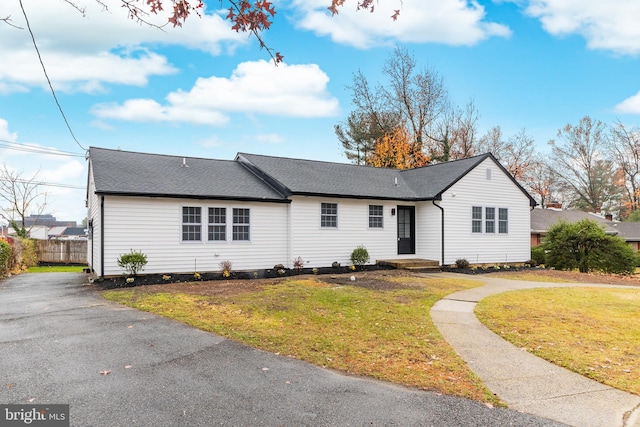 single story home featuring a front yard, fence, and roof with shingles