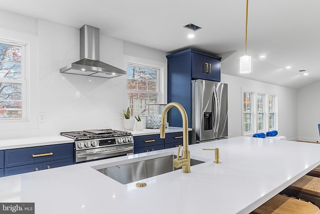 kitchen with a sink, wall chimney exhaust hood, blue cabinets, and stainless steel appliances