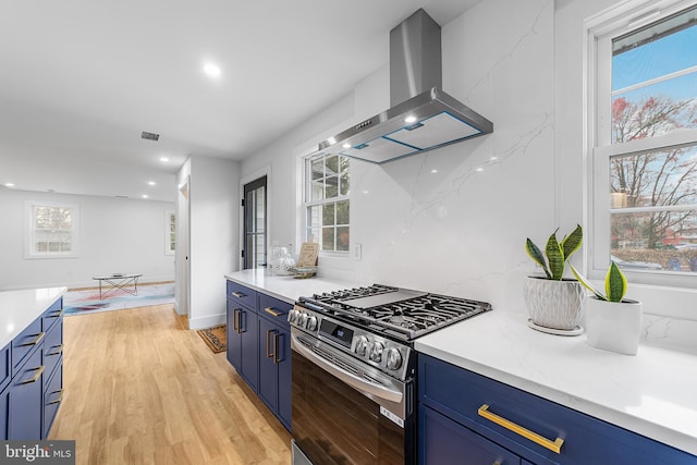 kitchen featuring range hood, blue cabinets, light wood-style floors, and stainless steel gas range