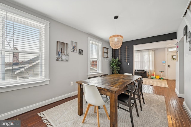 dining space with baseboards and wood-type flooring