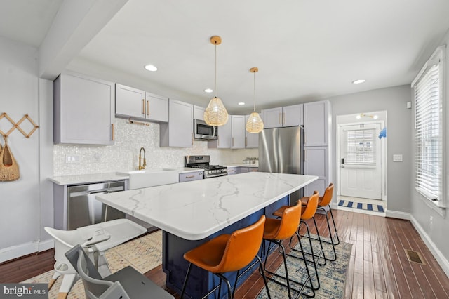 kitchen with a sink, decorative backsplash, appliances with stainless steel finishes, and dark wood-style floors