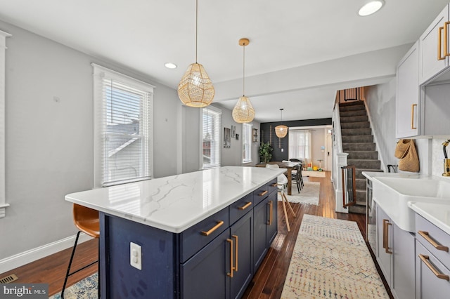 kitchen featuring blue cabinetry, a kitchen island, baseboards, recessed lighting, and dark wood-style floors