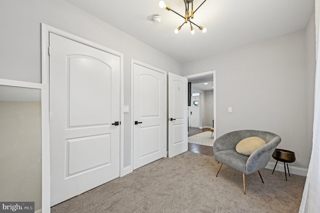 living area featuring an inviting chandelier, carpet, and baseboards