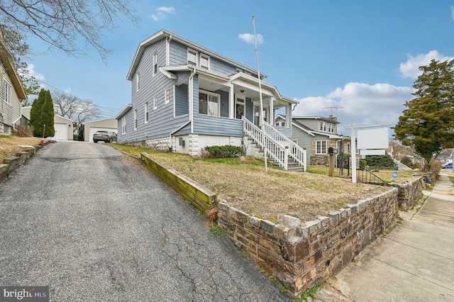 view of front facade with a garage, an outbuilding, and a porch