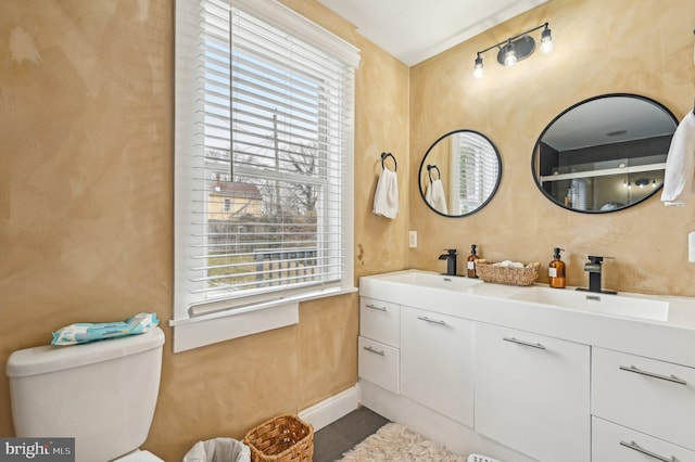 bathroom featuring a sink, toilet, and double vanity