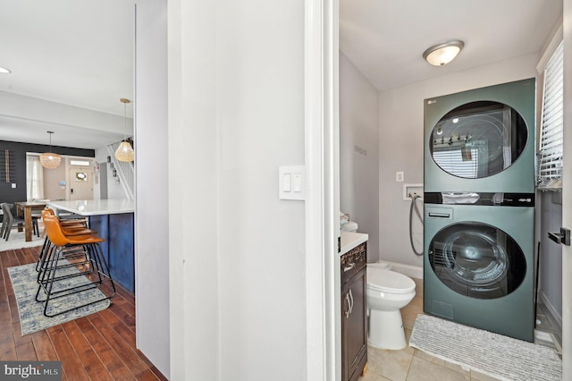 laundry area featuring laundry area, stacked washer and clothes dryer, and wood finished floors