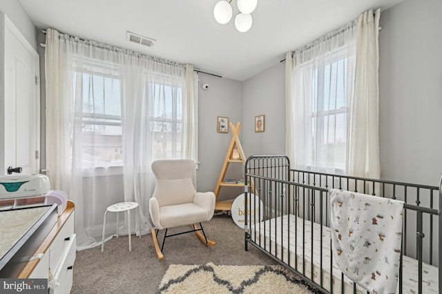 bedroom featuring visible vents, carpet, and a nursery area