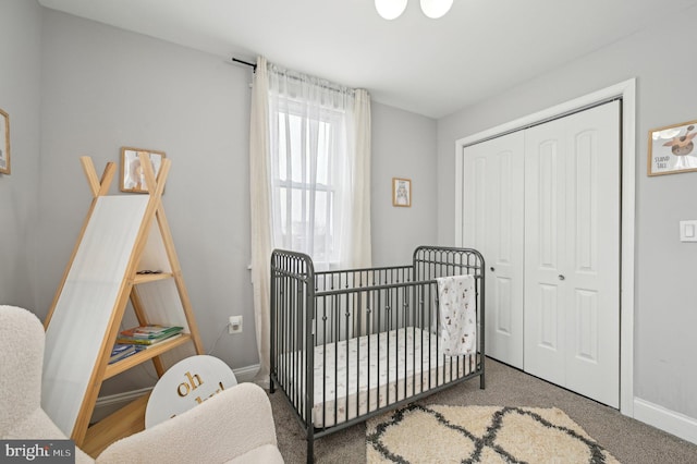 bedroom featuring a crib, baseboards, and a closet