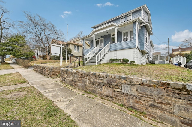 view of front of property featuring stairway, central AC unit, covered porch, and a front yard