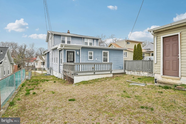 rear view of house featuring a gate, a yard, a deck, and fence