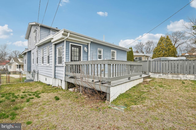 back of property with a gate, fence, a yard, and a wooden deck