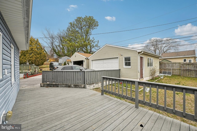 deck featuring an outbuilding, a yard, fence, and a detached garage