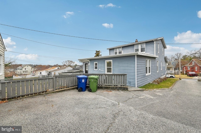 rear view of property featuring fence, a residential view, and a chimney