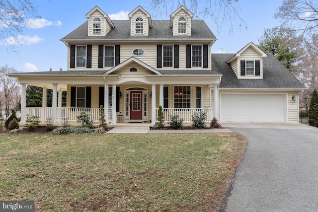 view of front of house featuring a garage, driveway, covered porch, and a front lawn