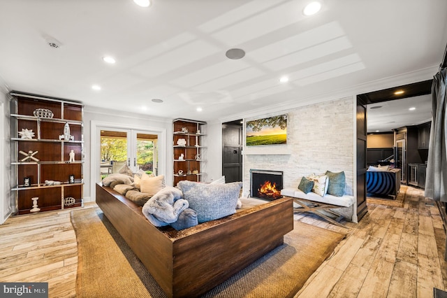 living room with a stone fireplace, light wood-style flooring, and ornamental molding