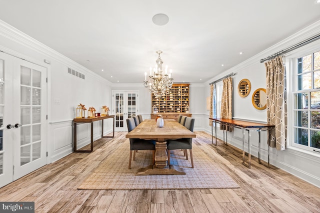 dining area featuring french doors, wainscoting, wood finished floors, and crown molding