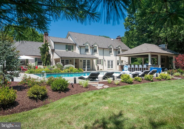 back of house with a gazebo, french doors, a chimney, a yard, and an outdoor pool