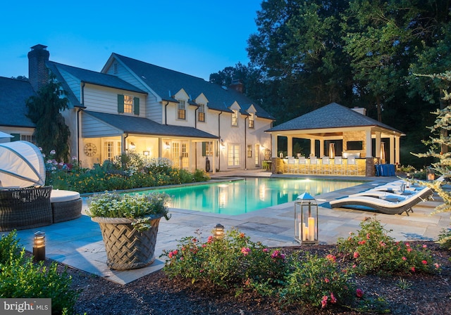 pool featuring an outdoor structure, a patio area, and an exterior structure