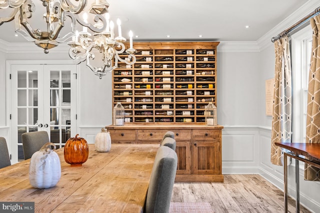 wine cellar with crown molding, a chandelier, wainscoting, french doors, and wood finished floors