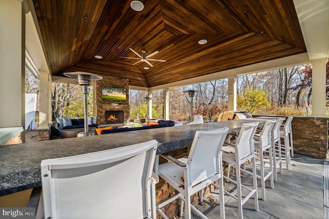 view of patio / terrace featuring an outdoor bar, an outdoor living space with a fireplace, and ceiling fan