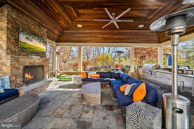 view of patio / terrace featuring an outdoor living space with a fireplace, exterior kitchen, a gazebo, area for grilling, and a ceiling fan