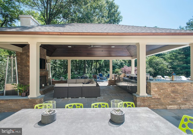 view of patio with a gazebo, outdoor dry bar, and an outdoor living space with a fireplace