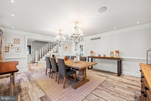 dining room with visible vents, light wood-style flooring, ornamental molding, stairway, and a chandelier