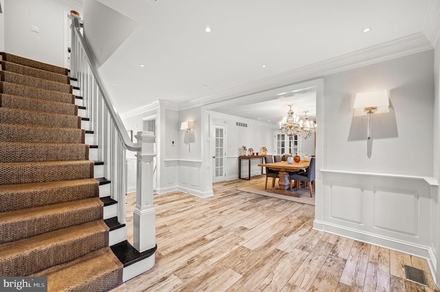 entryway with visible vents, a wainscoted wall, stairs, light wood-style floors, and a decorative wall